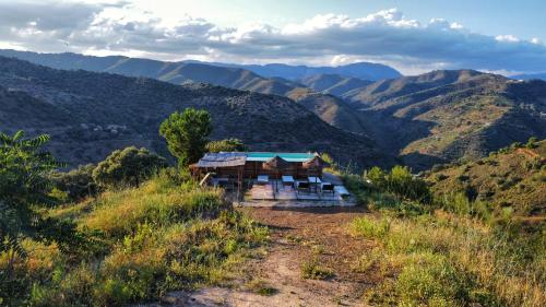 una casa en una colina con montañas en el fondo en Finca Serrato, en Colmenar