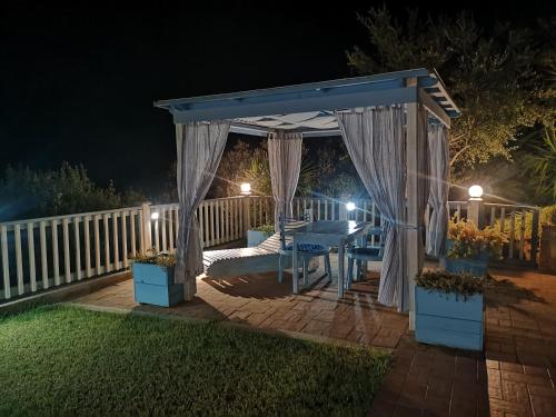 a gazebo with a bed and a table at night at Nel verde del Villaggio - Casetta Celeste in Gonnesa