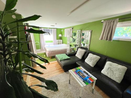 a living room with a black couch and a green wall at Lovely cottage by the south coast in Trelleborg