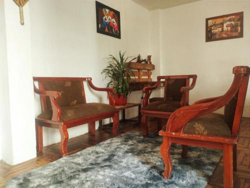 uma sala de estar com três cadeiras e um tapete em Villa bonita em Baños
