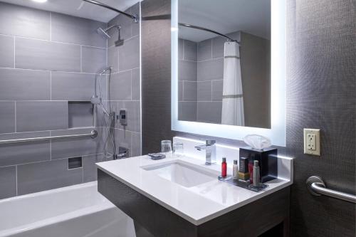 a bathroom with a sink and a tub and a mirror at Marriott Indianapolis North in Indianapolis