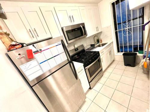 a kitchen with a stainless steel refrigerator and white cabinets at Nice 2 bedrooms apartament 10 minutes to Times Square in Weehawken
