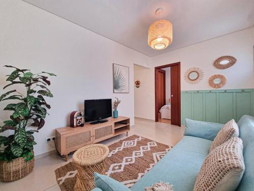 a living room with a blue couch and a tv at Casa Cais Novo in Viana do Castelo