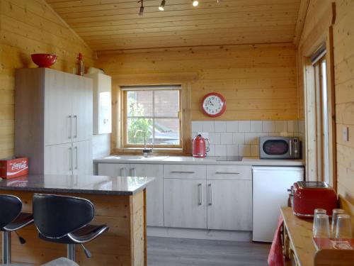 a kitchen with white cabinets and a clock on the wall at Baytree Lodge - Uk13322 in Melbourne