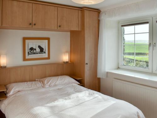 a bedroom with a white bed and a window at The Bothy in Old Hutton