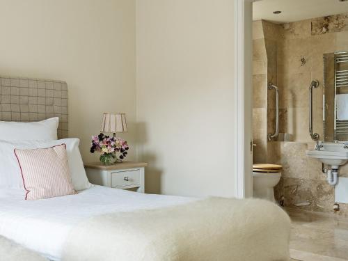 a bedroom with a white bed and a sink at Hungate Garden Cottage in Pickering