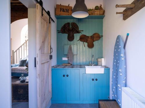 een keuken met een blauwe kast en een wastafel bij Tack Room in Benniworth