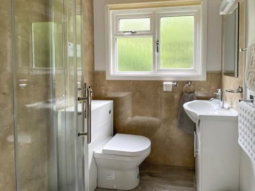 a bathroom with a toilet and a sink and a window at Satchwell - Uk31538 in Kirkhill