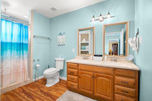 a bathroom with a sink and a toilet and a mirror at Serene Beachside Getaway - 77 Steps To The Ocean in Galveston