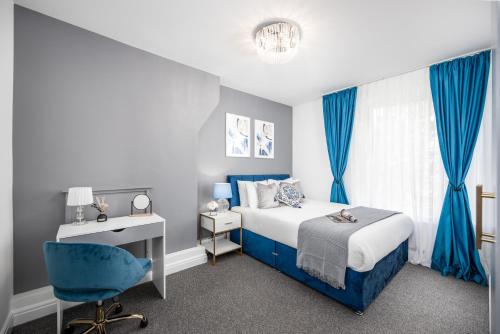 Schlafzimmer mit einem blauen Bett, einem Schreibtisch und einem Stuhl in der Unterkunft Cosy 4-Bedroom Apartment next to Borough in London