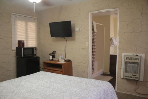 1 dormitorio con 1 cama y TV en la pared en Grand Canyon West Hotel Sheps Miners Inn en Chloride