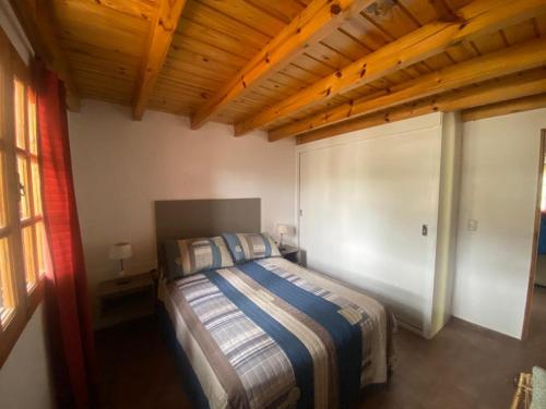 a bedroom with a bed and a wooden ceiling at LA NEGRITA in Ciudad Lujan de Cuyo