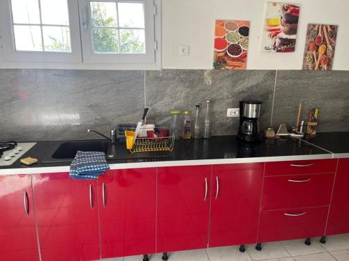 een keuken met rode kasten en een zwart aanrecht bij La Villa Les Cythos 1 in Le Lamentin