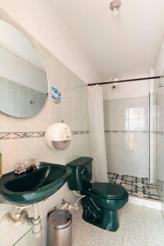 a bathroom with a green toilet and a sink at Letto Hostal in Rionegro