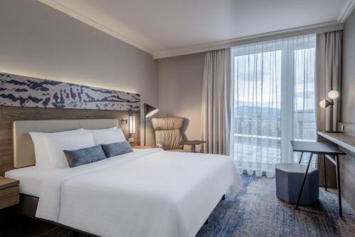 Un dormitorio con una gran cama blanca y una ventana en Courtyard by Marriott Linz en Linz