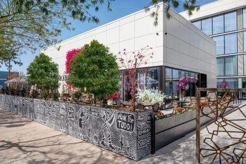 a white building with plants on a fence at The ENGLiSH Hotel, Las Vegas, a Tribute Portfolio Hotel in Las Vegas