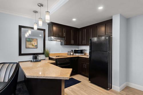a kitchen with a black refrigerator and wooden cabinets at City Express by Marriott Manhattan Beach in Manhattan Beach