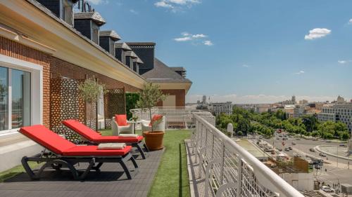a balcony with red chairs and a view of a city at NH Collection Madrid Col&oacute;n in Madrid