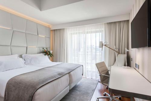 a hotel room with a large bed and a desk at NH Collection Madrid Colón in Madrid