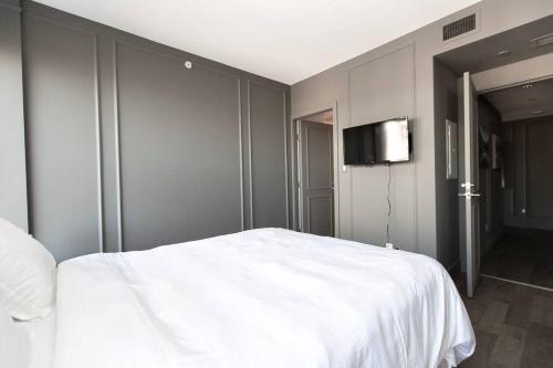 a bedroom with a white bed and a flat screen tv at Waterfalls Hotel in Downtown With Stunning Views! in Victoria