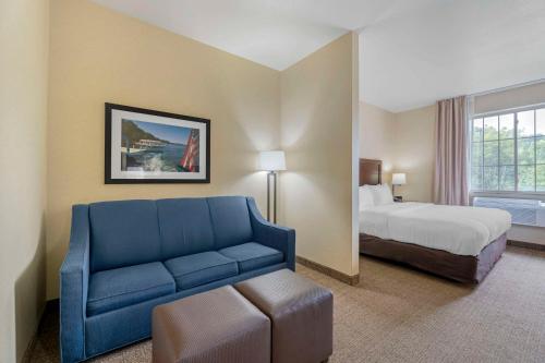 Habitación de hotel con cama y sofá azul en Comfort Suites Lake Geneva East, en Lake Geneva
