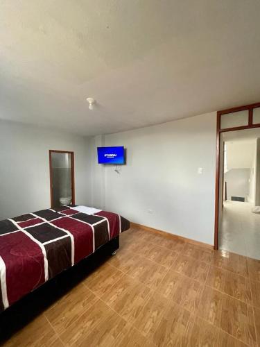 1 dormitorio con 1 cama y TV en la pared en Hostal Colonial en Cajamarca