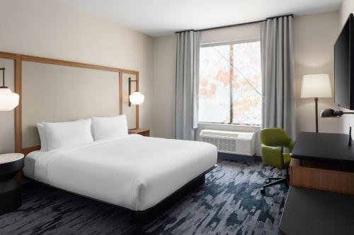 a hotel room with a large white bed and a window at Fairfield by Marriott Inn & Suites Whitsett Greensboro East in Whitsett