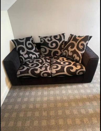 Un sofá negro con almohadas blancas y negras. en The dublin packet family room, en Holyhead