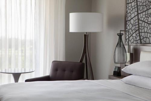 a bedroom with a chair and a lamp and a bed at Marriott Orlando Airport Lakeside in Orlando