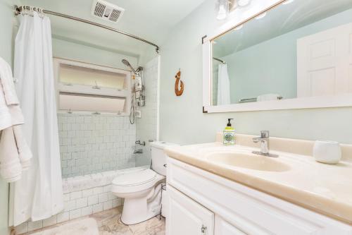 a white bathroom with a sink and a toilet at Tranquil Marina Front Pool House Resort in Honolulu