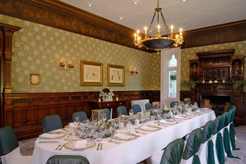 a long table in a room with green chairs at Delta Hotels by Marriott Breadsall Priory Country Club in Derby