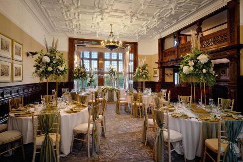 a banquet hall with tables and chairs and flowers at Delta Hotels by Marriott Breadsall Priory Country Club in Derby