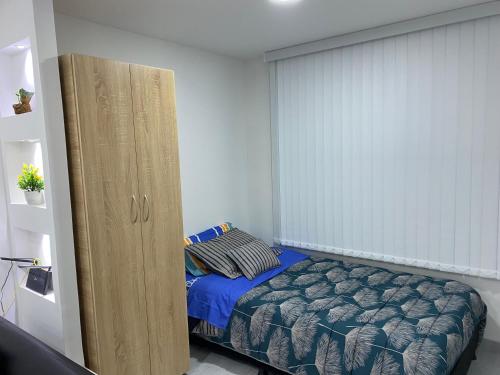 um pequeno quarto com uma cama e uma grande janela em Agradable apartamento norte calle 170 em Bogotá