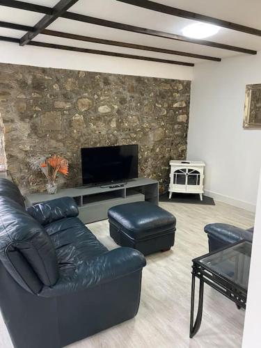 a living room with a couch and a flat screen tv at Beautiful renovated former coach house in Llandeilo
