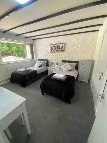 a bedroom with two beds and a table and a desk at Beautiful renovated former coach house in Llandeilo
