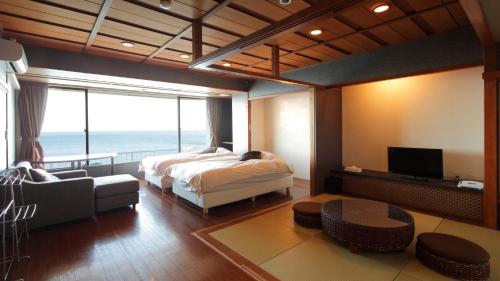 a bedroom with a bed and a view of the ocean at Atagawa Yamatokan in Higashiizu
