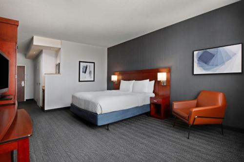 um quarto de hotel com uma cama e uma cadeira em Courtyard Kansas City at Briarcliff em Kansas City