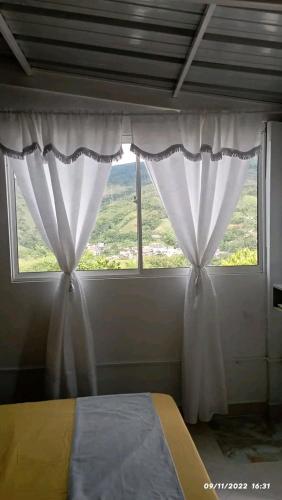 um quarto com uma cama e uma janela com cortinas em Mirador del fuerte em São Rafael
