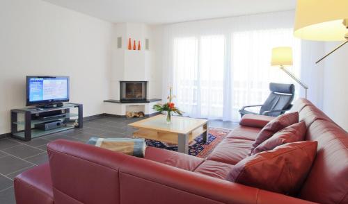 a living room with a red couch and a tv at Apartments Residenz Iris in Leukerbad