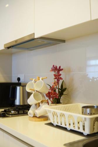 a kitchen counter with a dish drying rack and flowers at Serini Gateway Melawati in Kuala Lumpur