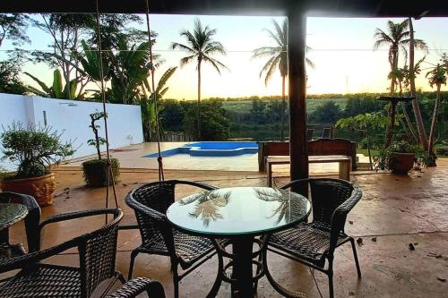 a table and chairs on a patio with a pool at Charmosa Casa no Lago in Ribeirão Preto