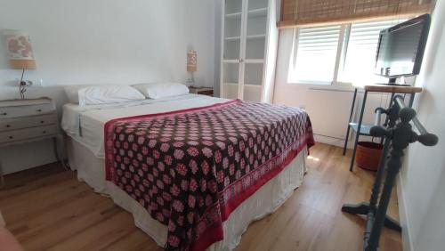 um quarto com uma cama com um cobertor vermelho e branco em Apto. en la playa del parque natural los Turuños em El Puerto de Santa Maria