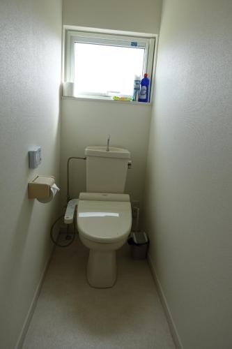 a small bathroom with a toilet with a window at 東神楽大学ゲストハウス in Higashikagura
