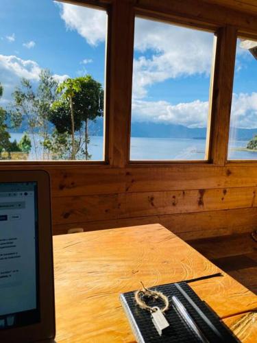 a table with a laptop computer on a table with windows at Cabaña en La Laguna de la Cocha in Pasto
