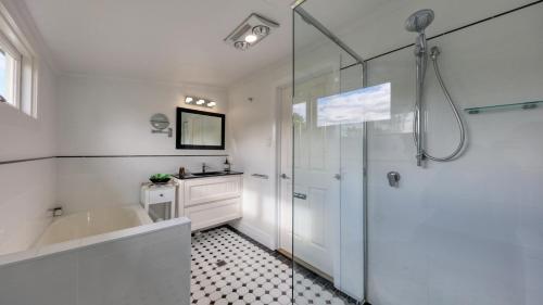 a white bathroom with a tub and a shower at Creekview Cottage - 70 Lock Street in Stanthorpe