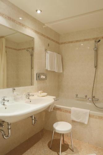 a bathroom with a sink and a tub and a mirror at Hotel Bristol in Karlovy Vary