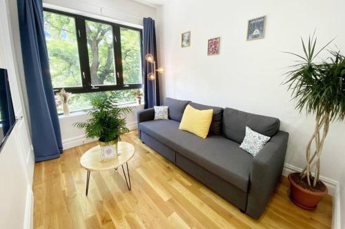 a living room with a couch and two potted plants at Cozy Bedroom - Shared Kitchen & Living room - Brooklyn Townhouse - 25min Manhattan in Brooklyn