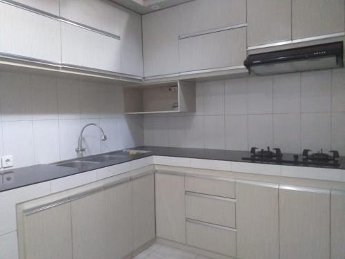 a kitchen with white cabinets and a sink at Juicezzy Home in Panji