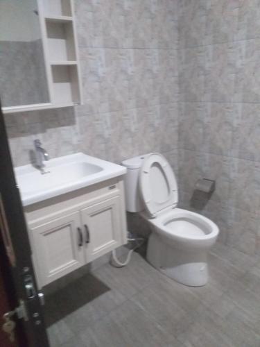 a bathroom with a white toilet and a sink at Juicezzy Home in Panji