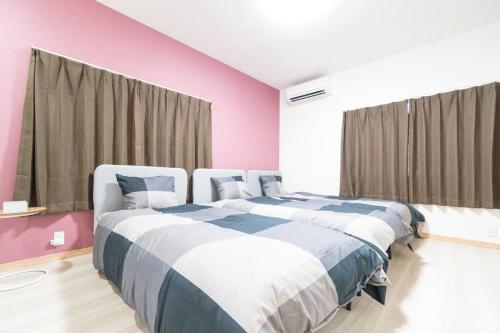 2 łóżka w pokoju w kolorze różowym i niebieskim w obiekcie LAINA MINOH＊1棟貸切＊ w mieście Minoo